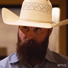 a man with a beard wearing a cowboy hat and a netflix logo