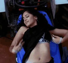 a woman is laying on a blue couch with her shirt off and her stomach exposed .