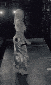 a black and white photo of a woman dancing on a stage .