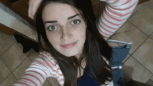 a woman is taking a selfie with her hand on her head while wearing a striped shirt .