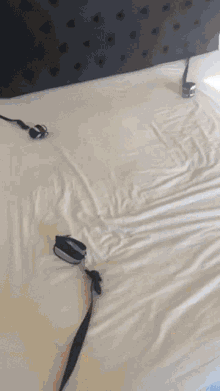 a bed with a black headboard and white sheets has a pair of headphones on it