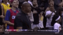 a crowd of people watching a basketball game with a man wearing a blue shirt that says oklahoma