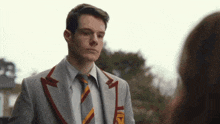 a man in a suit and tie is looking at a woman in a park .
