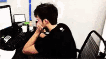 a man is sitting at a desk looking at a computer screen ..