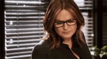 a woman wearing glasses looks down at something