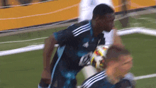 a soccer player wearing a blue adidas jersey kicks a soccer ball