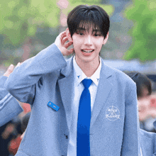 a young man wearing a blue jacket and tie with boys planet embroidered on the front