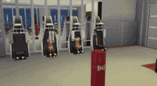 a man in a purple shirt stands in a gym next to a red punching bag with the letter m on it