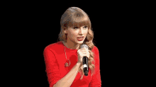 a woman in a red shirt is holding a microphone in her hand and talking into it .