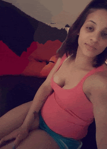 a woman in a pink tank top and blue shorts is taking a picture of herself