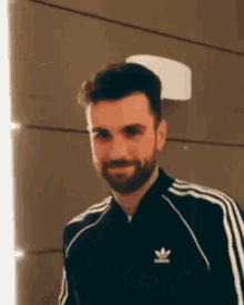 a man with a beard wears an adidas jacket