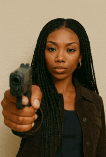 a woman in a brown jacket is pointing a gun towards the camera