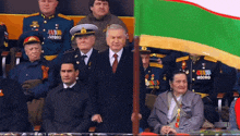 a man in a suit and tie holds a flag with the letters aa on it