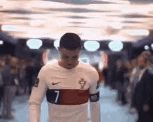 a soccer player in a white shirt is walking through a crowd of people .
