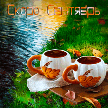 two cups of coffee sit on a wooden tray in front of a river with the words скоро сентябрь written in orange