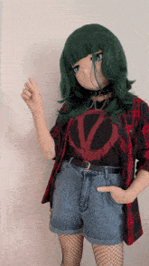 a girl with green hair is wearing a red and black plaid shirt