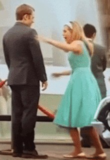 a man in a suit and a woman in a green dress are standing next to each other