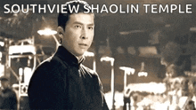 a black and white photo of a man standing in front of a building with the words `` southview shaolin temple '' above him .