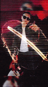 a man wearing sunglasses is holding a guitar in front of a red background