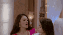 two women are standing next to each other in a room and one is holding the other 's neck .
