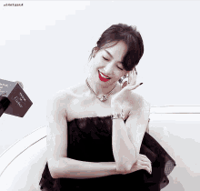 a woman wearing a black strapless dress with a cartier box in the background
