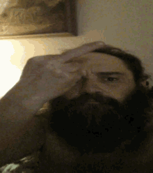 a man with a beard is making a face with his hand
