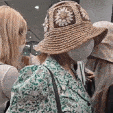 a woman wearing a straw hat and a green dress is talking to another woman .