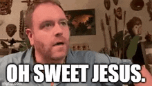 a man with a beard is making a funny face and saying `` oh sweet jesus '' in a living room .