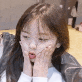 a close up of a girl making a funny face with her hands on her face .