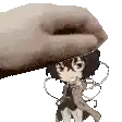 a hand is holding a small cartoon character on top of a white surface .