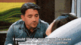 a man in a denim shirt is talking to a woman in a hospital bed who is laying in a hospital bed .