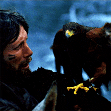 a man with a beard holds an eagle in his hands