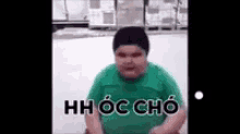 a fat boy wearing a green shirt and black hat is sitting in the snow .