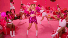 a woman in a pink outfit is dancing in front of a pink background
