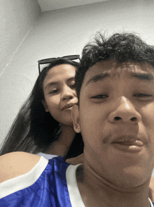 a man and a woman are posing for a picture and the man is wearing a blue tank top