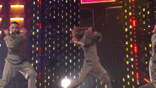 a group of people are dancing on a stage with a pink square in the background