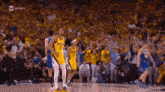 a group of basketball players are standing on a court in front of a crowd of fans .