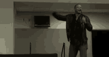 a man in a black jacket is standing in front of a microphone and talking into it .