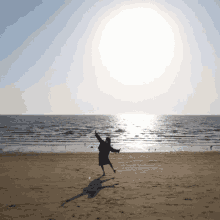 a woman is jumping in the air on a beach near the ocean