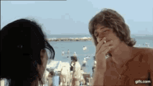 a man is smoking a cigarette while a woman looks on .