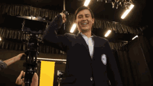 a man in a suit stands in front of a camera with a yellow banner behind him that says " cube "
