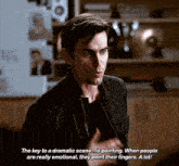 a man in a black jacket is talking about a dramatic scene .