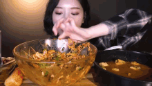 a woman eating a bowl of food with a spoon