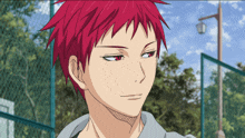 a man with red hair and red eyes is standing in front of a fence