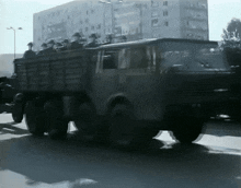a military truck is driving down a city street