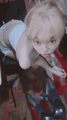 a girl with blonde hair is laying on the floor next to a camera