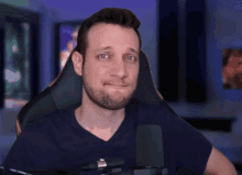 a man with a beard sits in a chair in front of a microphone