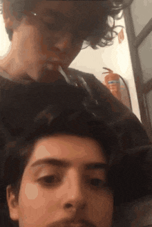 a man is smoking a cigarette next to another man 's head