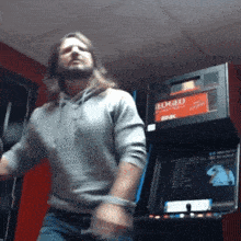 a man is dancing in front of an arcade machine that says nintendo