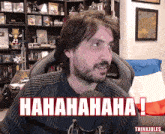 a man with a beard is sitting in front of a microphone with the words ' hahahaha ! ' written above him